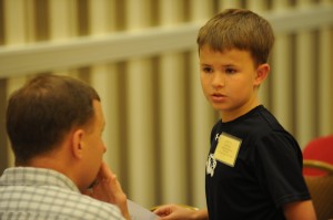 Evan Filer, a 10-year-old speller from McEowen Elementary School in Harrisonville, Mo., talks to his dad, Bill Filer, during the Scripps National Spelling Bee on Tuesday. (Photo Courtesy of Mark Bowen and the National Spelling Bee)