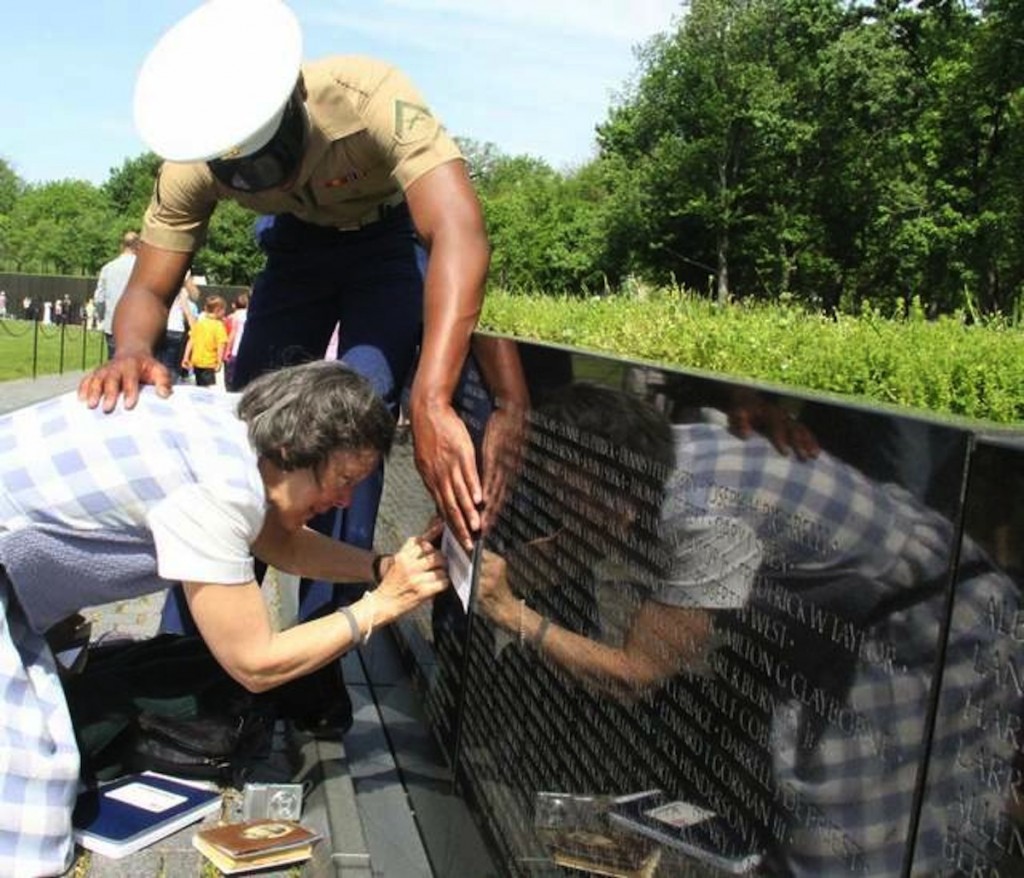 A Marine comforts L.S. Elisabeth Swiriduk as she traces the name of her father, Walter H. Mauldin, on the Vietnam Veterans Memorial. A May 11 ceremony honored the addition of the names of Mauldin and 13 other service members to the memorial. Mauldin died 46 years ago from cancer related to exposure to the herbicide Agent Orange. (Tammy Thueringer / Medill News Service)