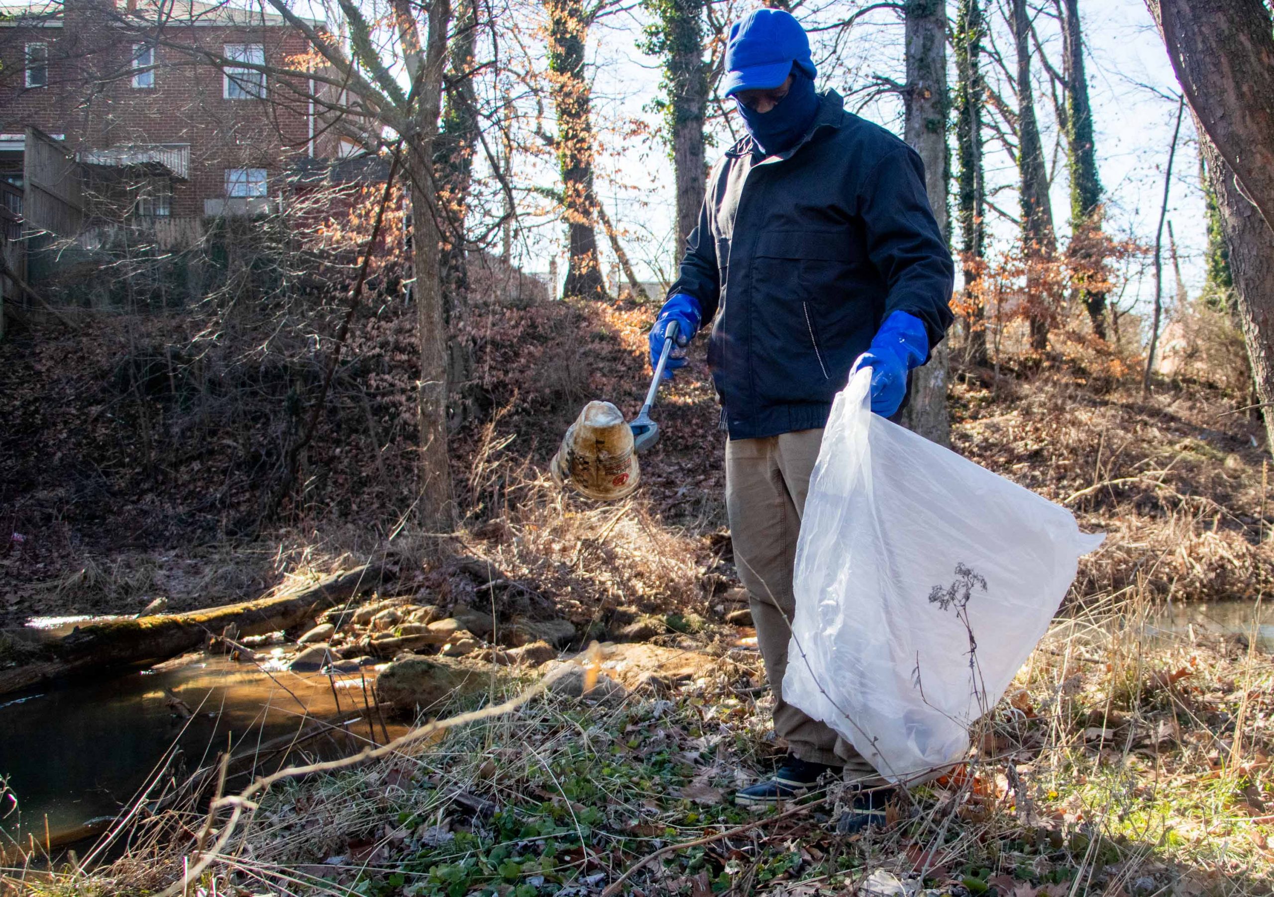 Clarence Elliott, a literacy teacher, picks up a plastic water bottle from near the Pope Branch Stream Saturday during the cleanup in honor of Martin Luther King Day. (Isabel Miller | Medill News Service)