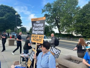 An individual holds a sign that reads "The Trump Fascist Regime Must Go Now!!!" outside the Supreme Court.